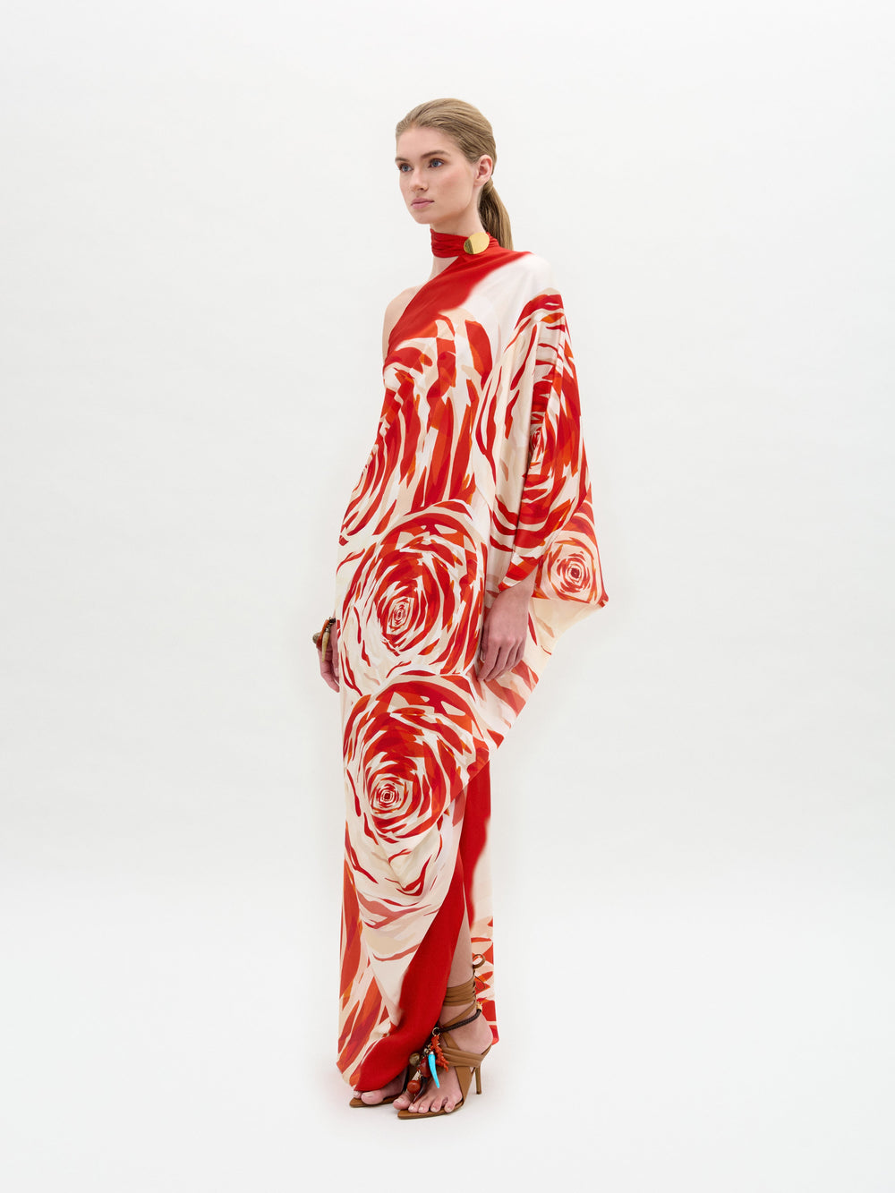 A person wearing the Dani Tunic with a long, flowing design featuring a red and white rose pattern stands against a plain background.