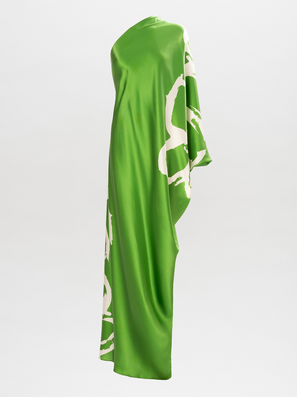 La túnica Inu es un elegante vestido de taller en tela italiana verde brillante con un llamativo diseño lateral abstracto en blanco, que muestra un escote asimétrico y una silueta fluida y drapeada sobre un fondo sencillo y de color claro.