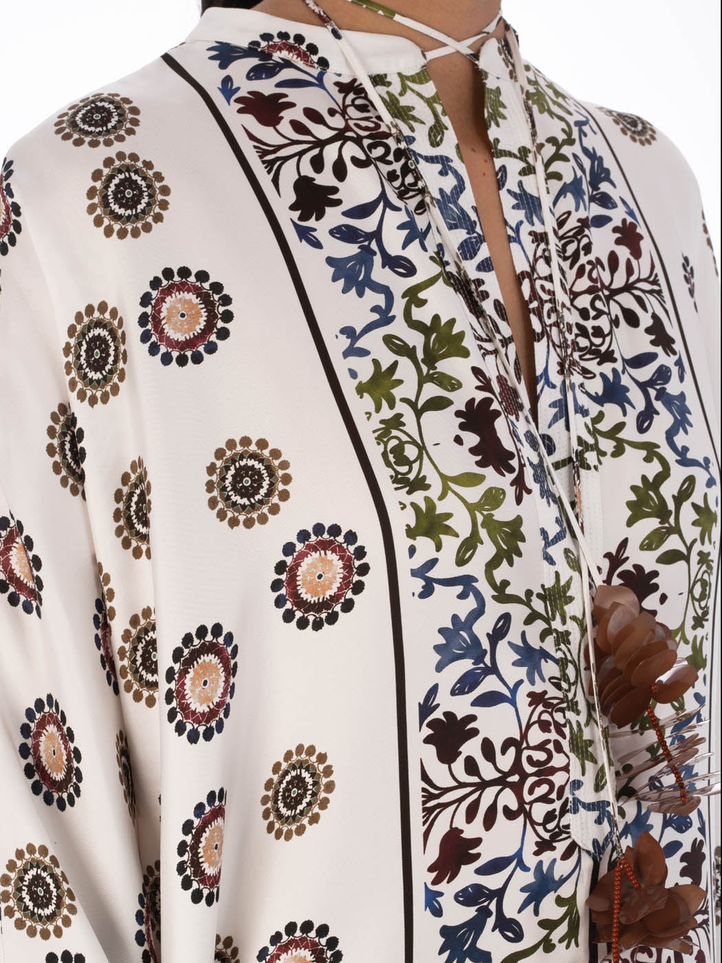 A long, white Elea Tunic Multi Sepia Floral with a mixed pattern of floral and circular designs, displayed on a transparent mannequin against a white background.