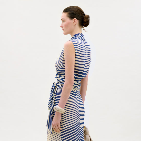 Woman wearing a blue and white striped dress against a plain background