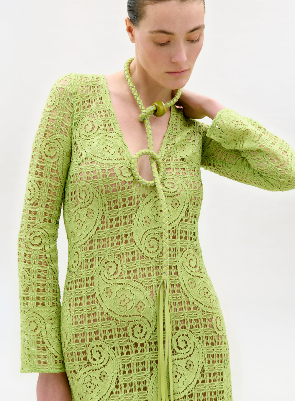 Woman wearing a green lace dress against a white background