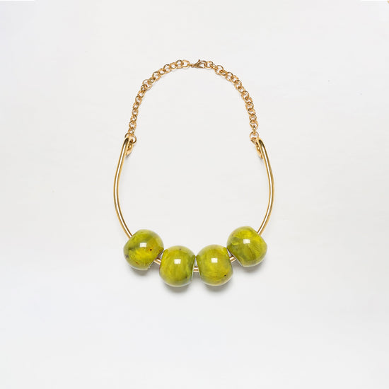 The Martini Chocker is a gold chain necklace featuring four large, glossy green beads on a curved gold bar, shown against a white background.
