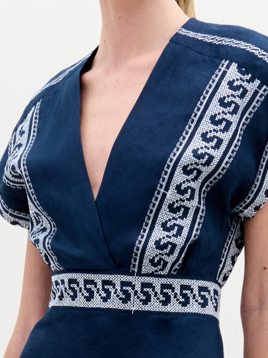 Alguien lleva el Vestido Ady, un llamativo minivestido azul con motivos geométricos blancos en el escote y la cintura. Fabricado en Colombia, tiene un escote en V profundo y mangas cortas. La tela texturizada y liviana realza su elegante diseño.