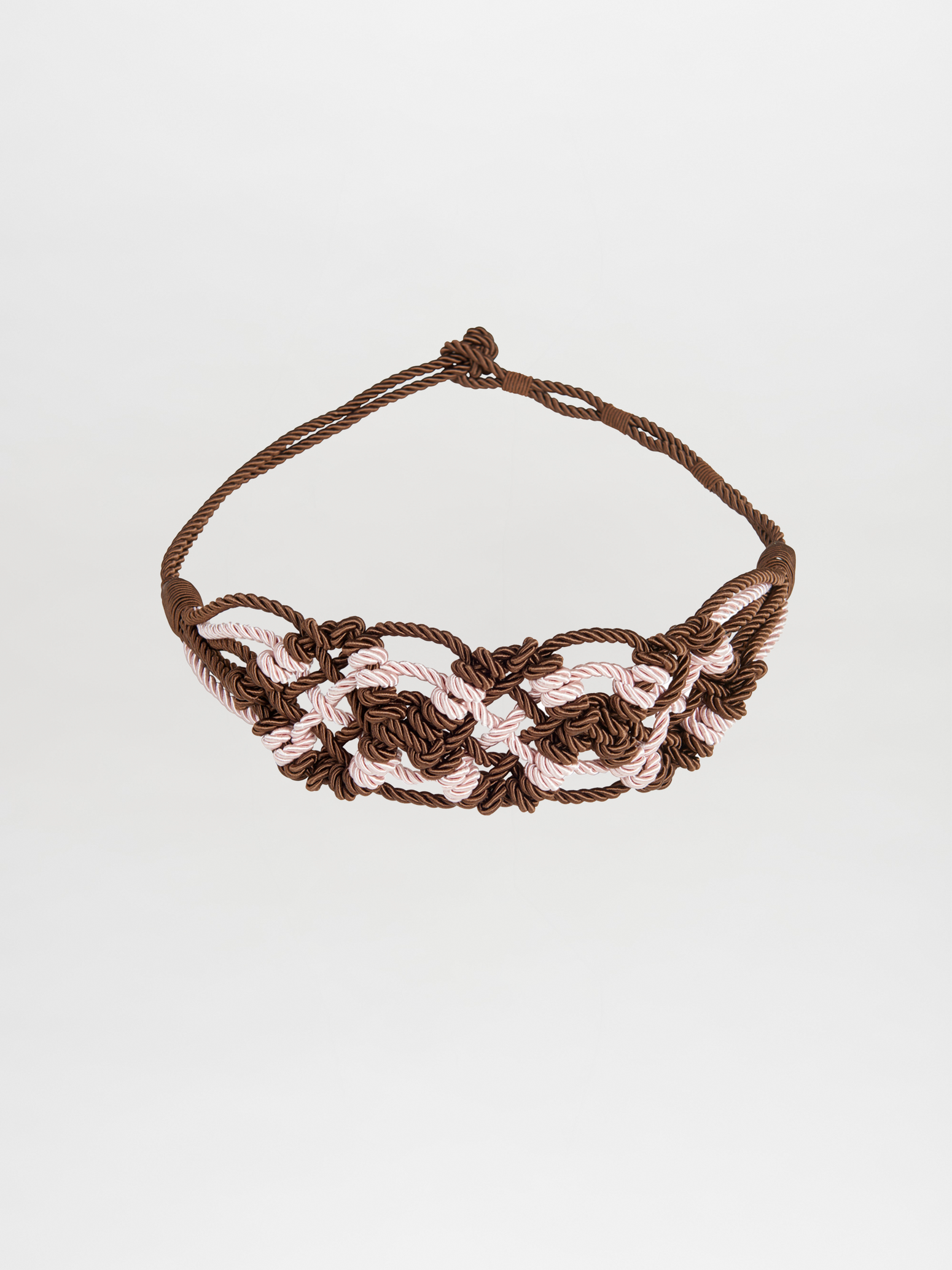 The Bresia Belt Brown Pink features intertwined brown and light pink cords that create a woven pattern reminiscent of nautical knots, set against a plain white background. This accessory adds a touch of elegance to any outfit and is ready to ship, arriving just days after ordering.