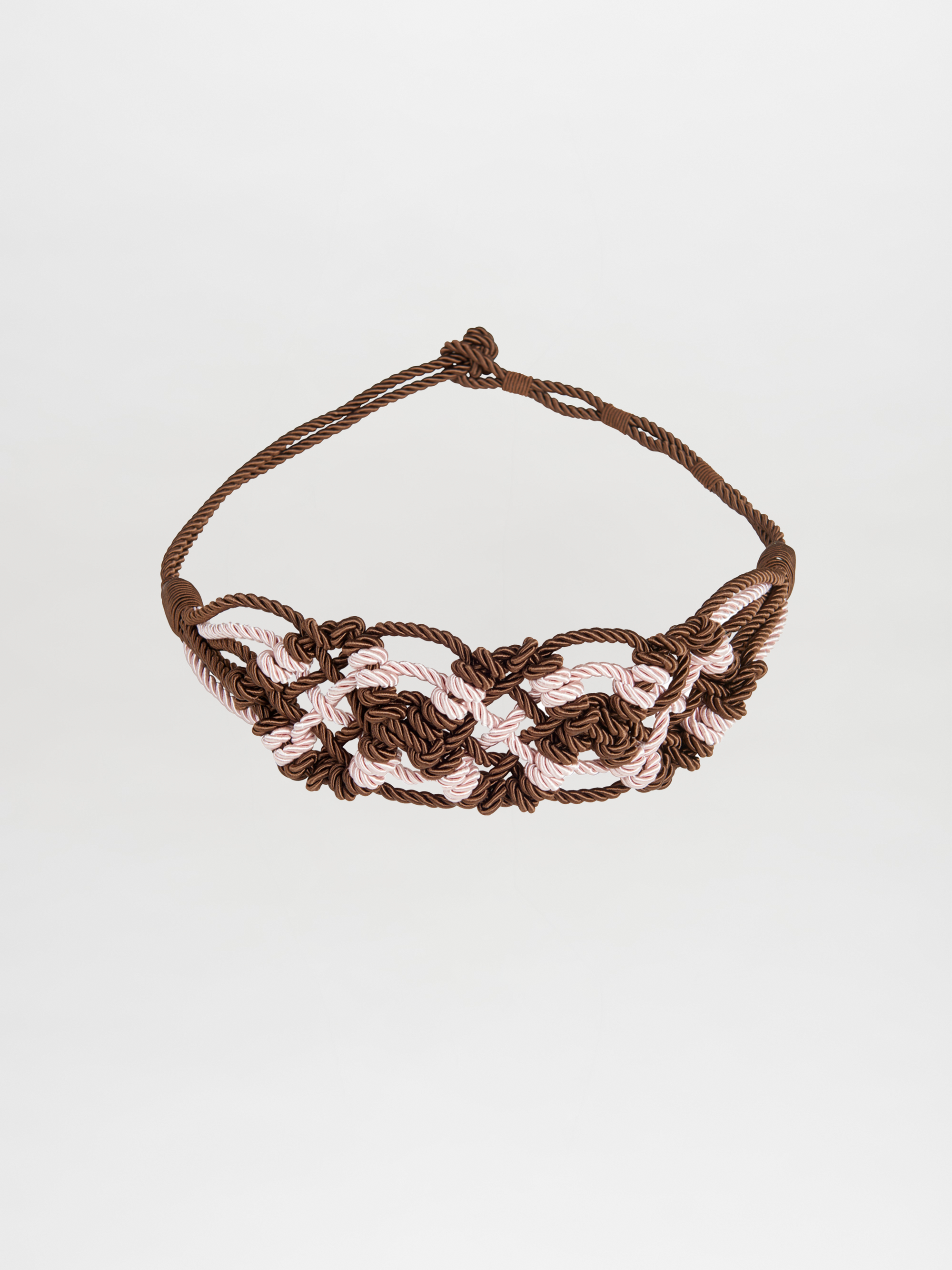 The Bresia Belt Brown Pink features intertwined brown and light pink cords that create a woven pattern reminiscent of nautical knots, set against a plain white background. This accessory adds a touch of elegance to any outfit and is ready to ship, arriving just days after ordering.
