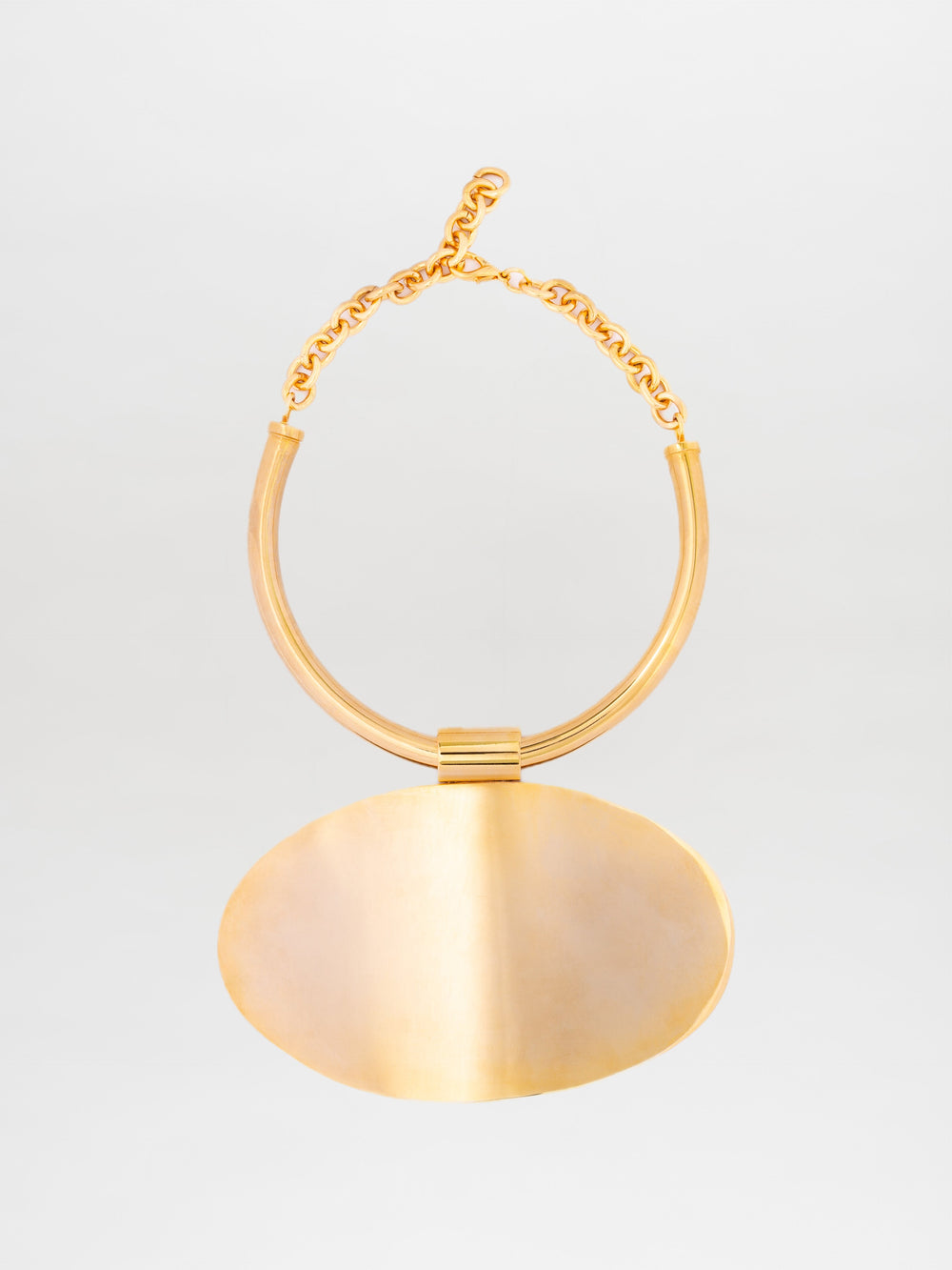 El collar Danielle presenta un diseño minimalista en tono dorado con un gran colgante ovalado y una cadena de eslabones. El colgante, fabricado en latón bañado en oro, tiene un acabado suave y reflectante. La cadena está elegantemente asegurada con un cierre de gancho.