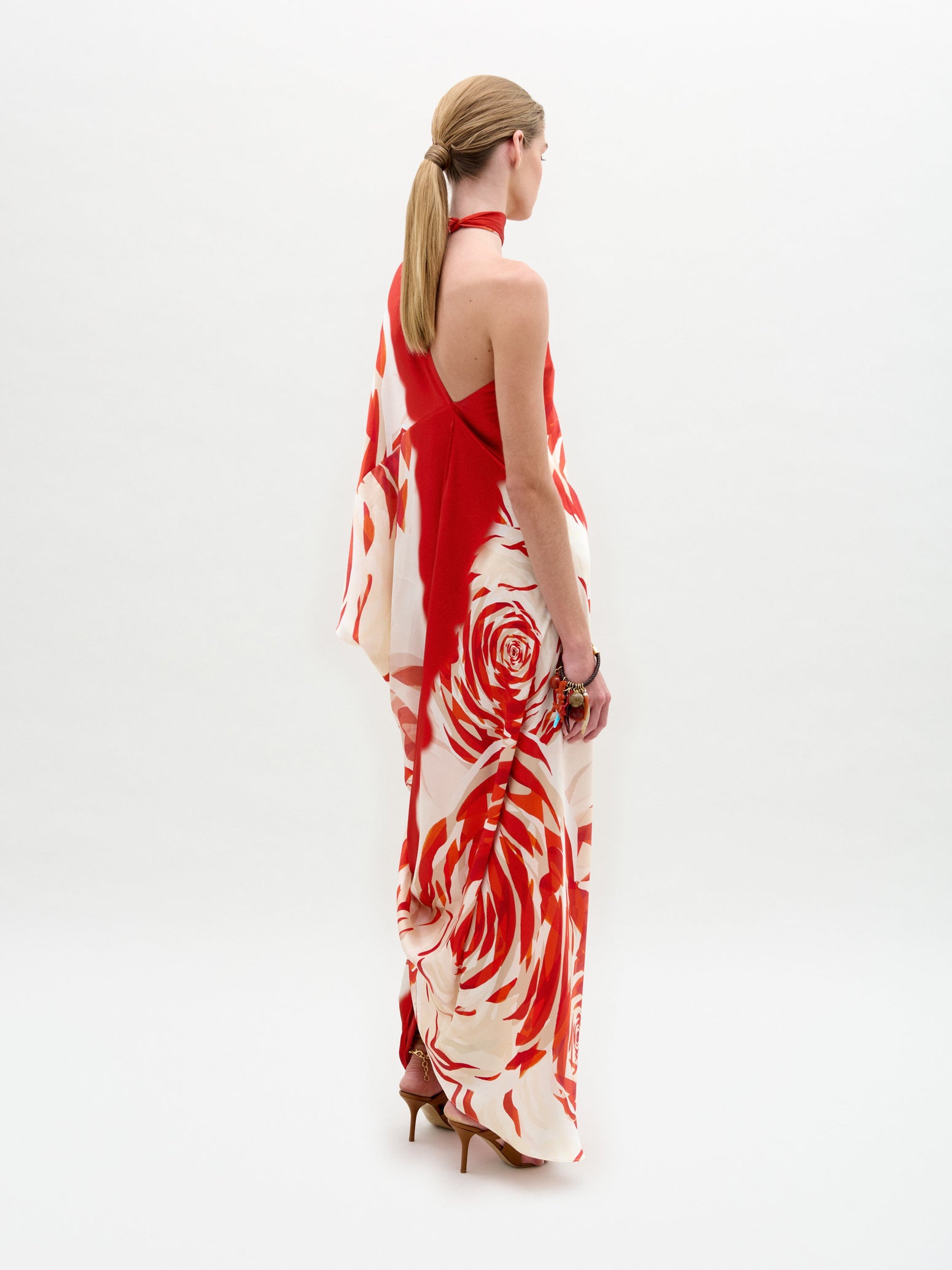 A person wearing the Dani Tunic with a long, flowing design featuring a red and white rose pattern stands against a plain background.