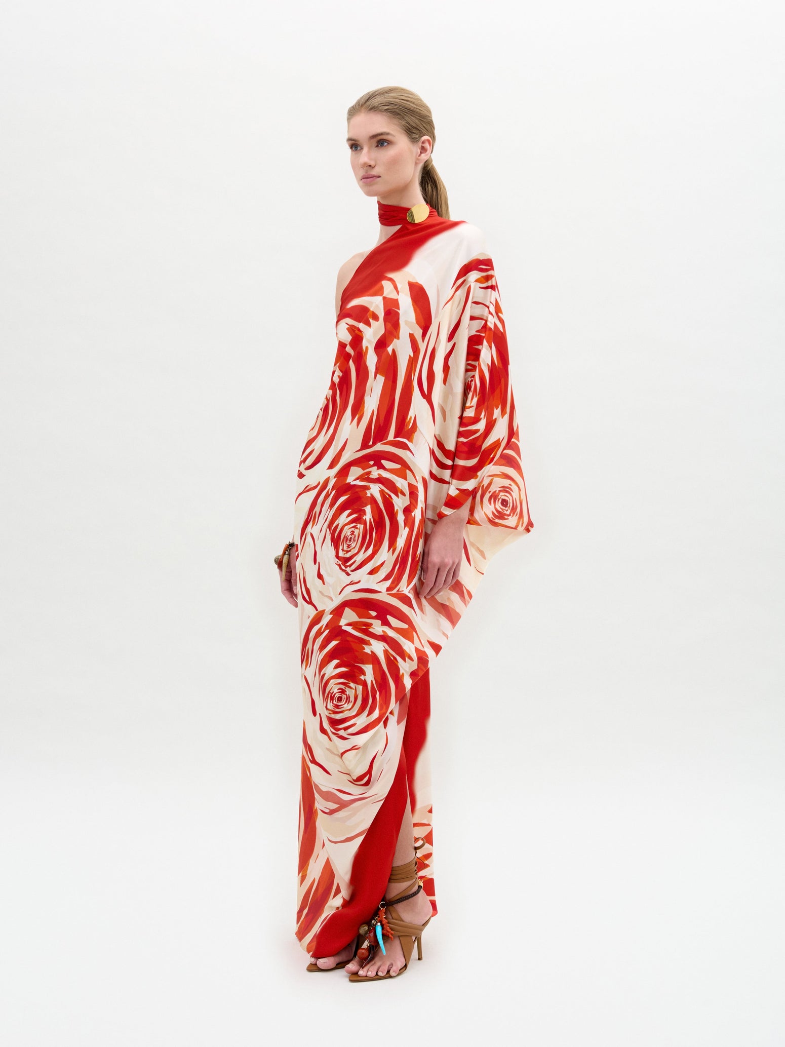 A person wearing the Dani Tunic with a long, flowing design featuring a red and white rose pattern stands against a plain background.