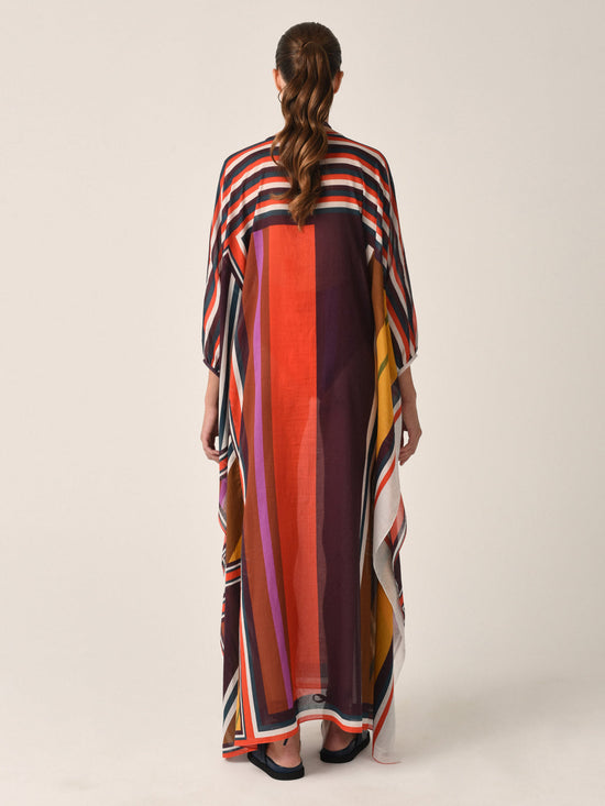 The Magel Kaftan Color Block Multi from the Resort 2023 collection is a multicolored striped piece featuring a keyhole neckline and tassel tie closure. This kaftan offers a loose, flowing fit with an asymmetric hem in color block multi pattern voile, ensuring both comfort and style.