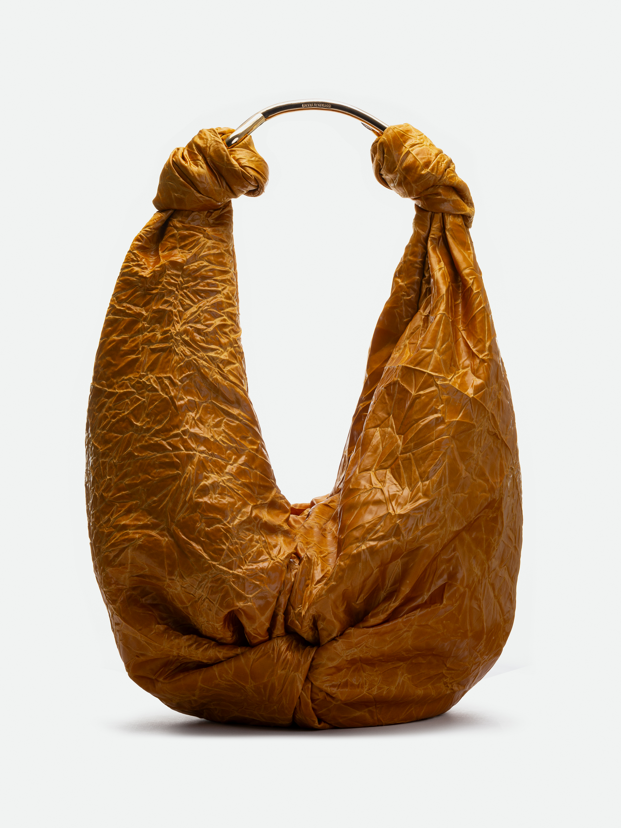 A person in a brown strapless outfit stands gracefully with a Sofia Bag Maxi, a large textured accessory, draped over their shoulder against a plain background.